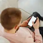 Homme sur son téléphone lisant une documentation de coaching.