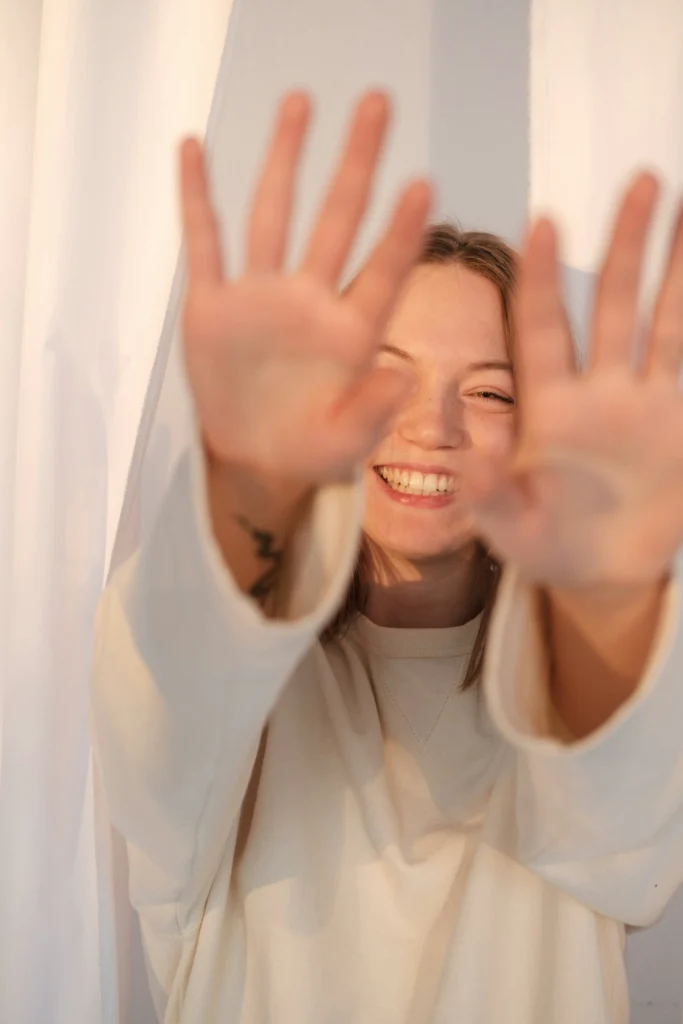 Femme souriante avec les mains tendues vers l’objectif, exprimant la liberté émotionnelle offerte par l’hypnothérapie à Jeumont.